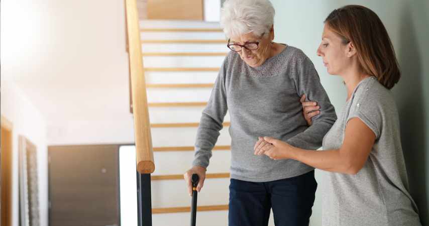 Home carer helping elderly person on the stairs