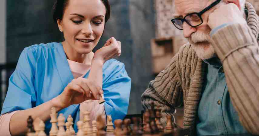 Home carer and elderly person playing chess